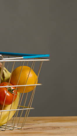 Vertical-Video-Shot-Of-Basic-Fresh-Fruit-And-Vegetable-Food-Items-In-Supermarket-Wire-Shopping-Basket-